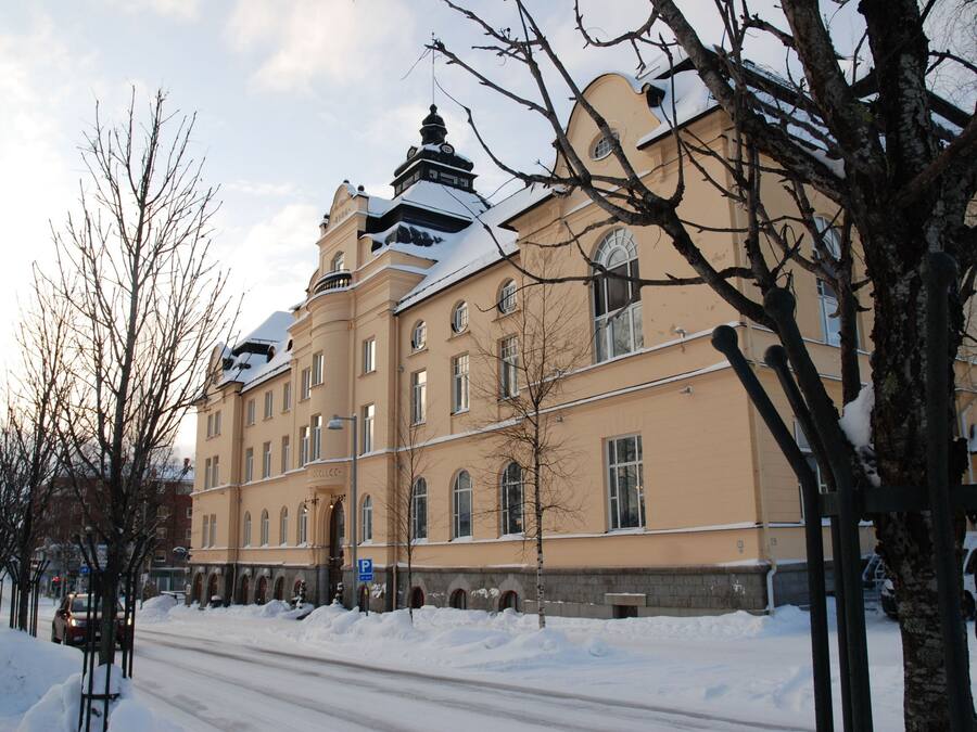 En stor, historisk byggnad med många fönster och ett snötäckt tak.