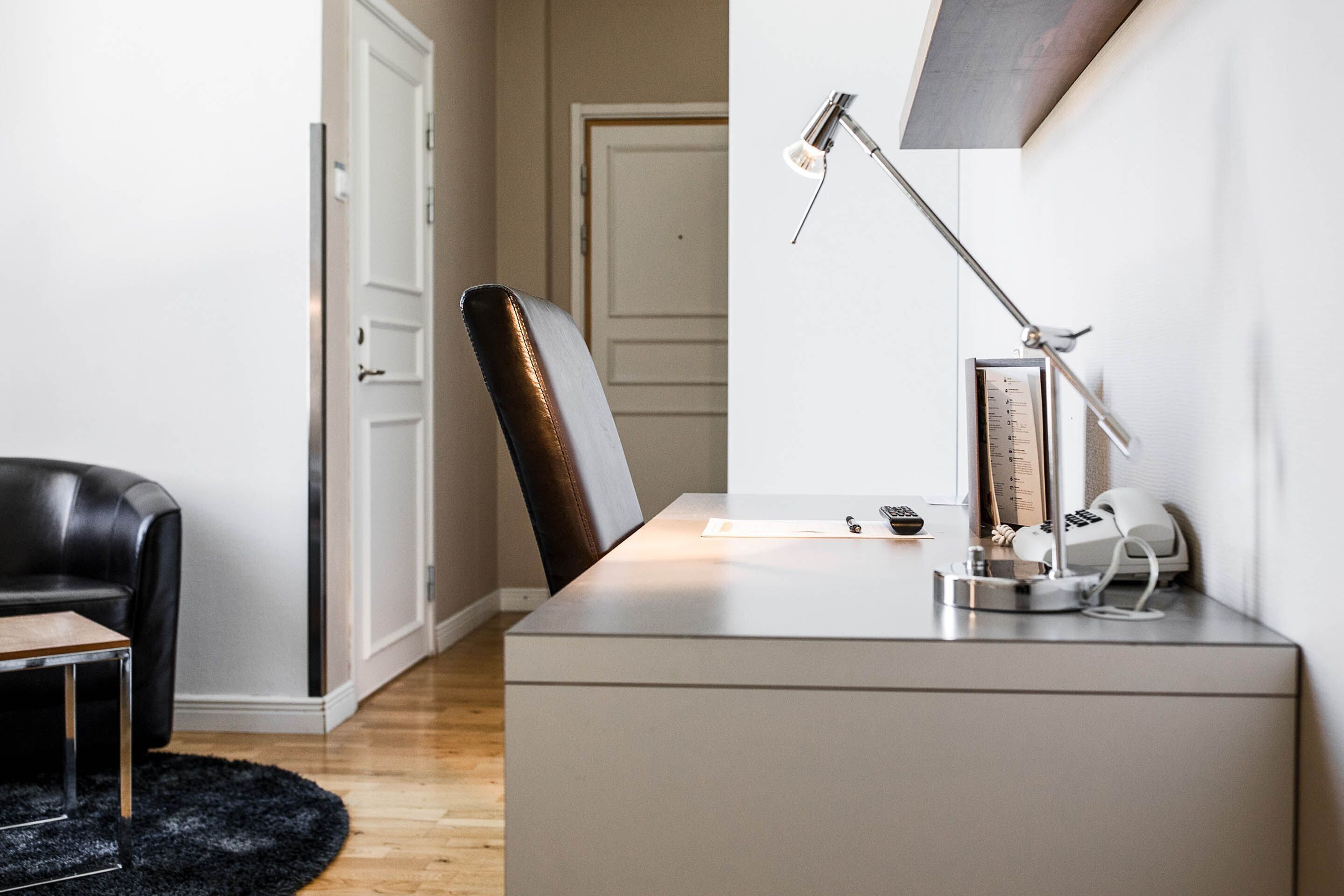 Un espace de bureau moderne comprenant un bureau, une chaise, une lampe et une petite table avec une lampe.