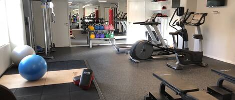 A gym with exercise equipment like treadmills, elliptical machines, and free weights.