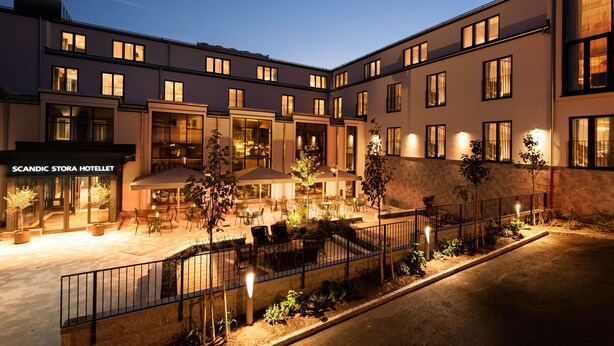 A hotel with outdoor seating, a staircase, and a well-lit entrance. - Scandic Stora Hotellet (Nykoping)
