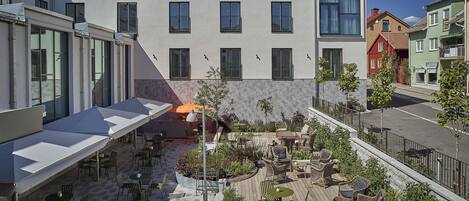 A courtyard with outdoor seating, a covered area, and a building with multiple windows.