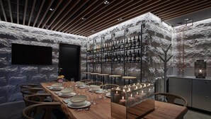 A modern dining area with a long wooden table set for six, surrounded by stone walls and a wine rack. - Scandic Stora Hotellet (Nykoping)