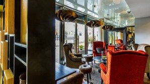 A modern interior with a glass wall, wooden shelving, and red and beige chairs. - Scandic Stora Hotellet (Nykoping)