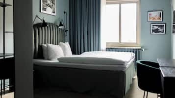 Un dormitorio con cama, escritorio, silla y ventana con cortinas.