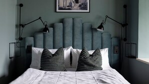 A bedroom with a bed, two bedside lamps, a framed picture on the wall, and a headboard with vertical panels. - Quality Hotel Carlia (Uddevalla)