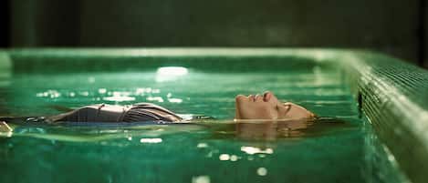 A swimming pool with clear water and a person floating in it.