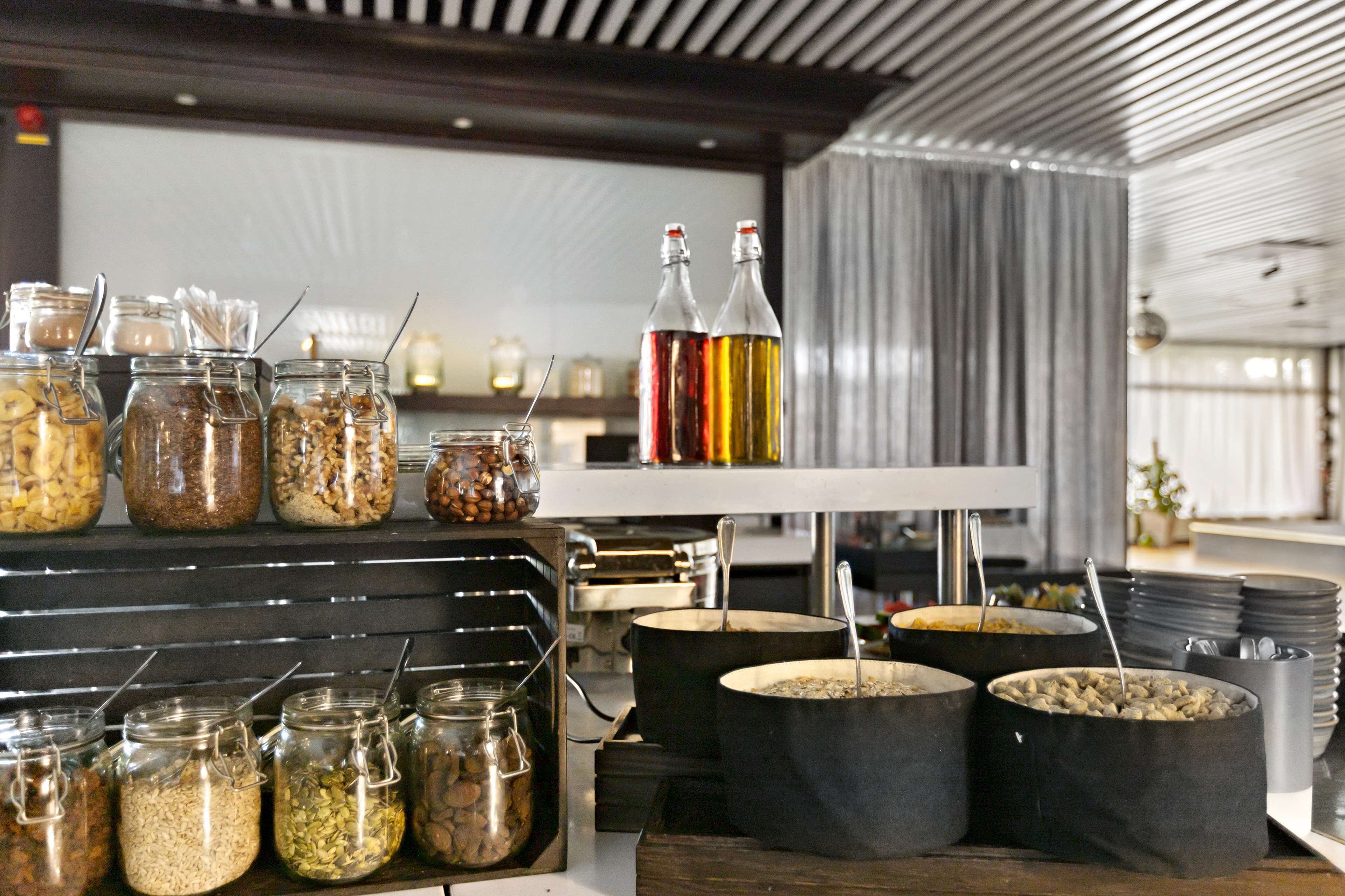 A buffet setup with various food items in jars and pots, a white counter, and bottles of sauces.