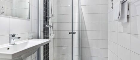 A modern bathroom with a glass shower enclosure, a white sink, and a towel rack.