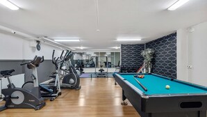 A gym with exercise bikes, a pool table, and a mirror. - Best Western Hotel Scheele (Köping)
