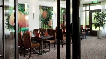 Un salón de conferencias de hotel con mesas, sillas, una alfombra estampada y un amplio ventanal con vistas.