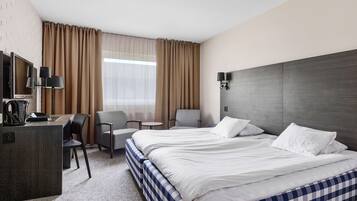 Habitación de hotel con dos camas, un escritorio, una silla, un televisor y una ventana con cortinas.