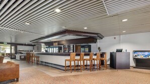 A modern bar area with a counter, bar stools, and a television screen. - Best Western Hotel Scheele (Köping)