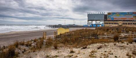 Una playa con un muelle, un pequeño edificio amarillo y un cartel grande.
