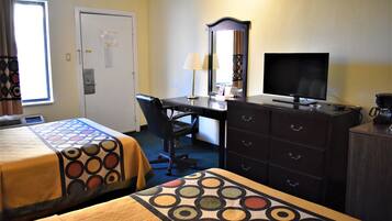 A hotel room with two beds, a desk with a computer, a dresser, and a television.