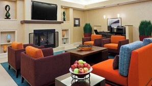 Uma sala de estar moderna com sofás, lareira, televisão de tela plana e mesa de centro com uma tigela de frutas.