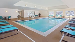 Uma grande piscina interior com várias espreguiçadeiras e um terraço solar.