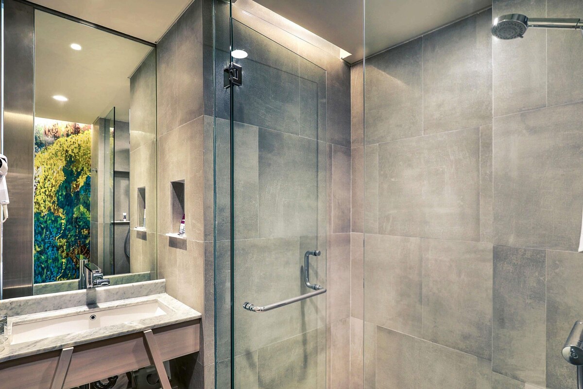 A modern bathroom with a glass-enclosed shower, a marble sink, and a towel rack.