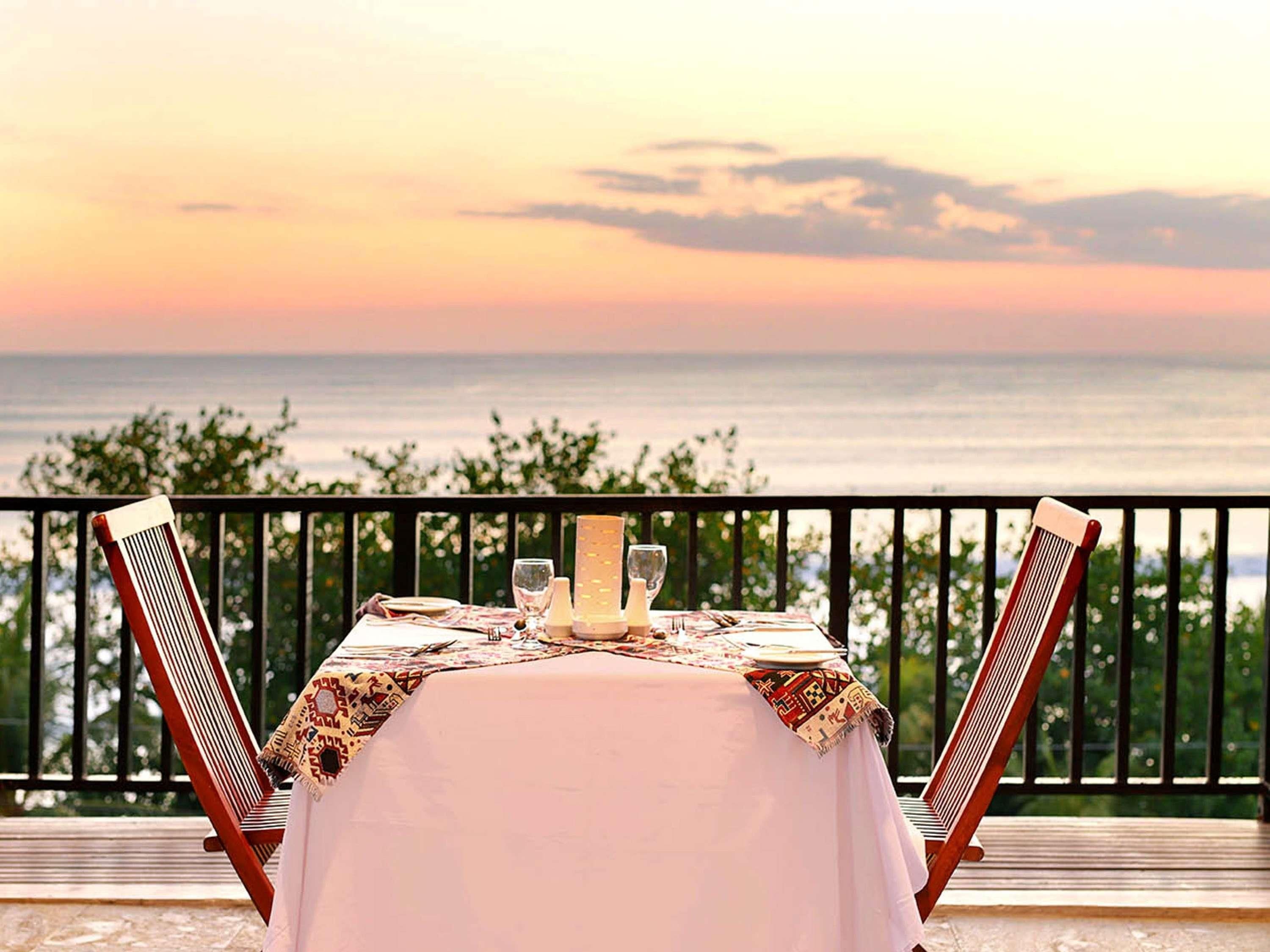 A table set for two with a view of the sea at sunset.