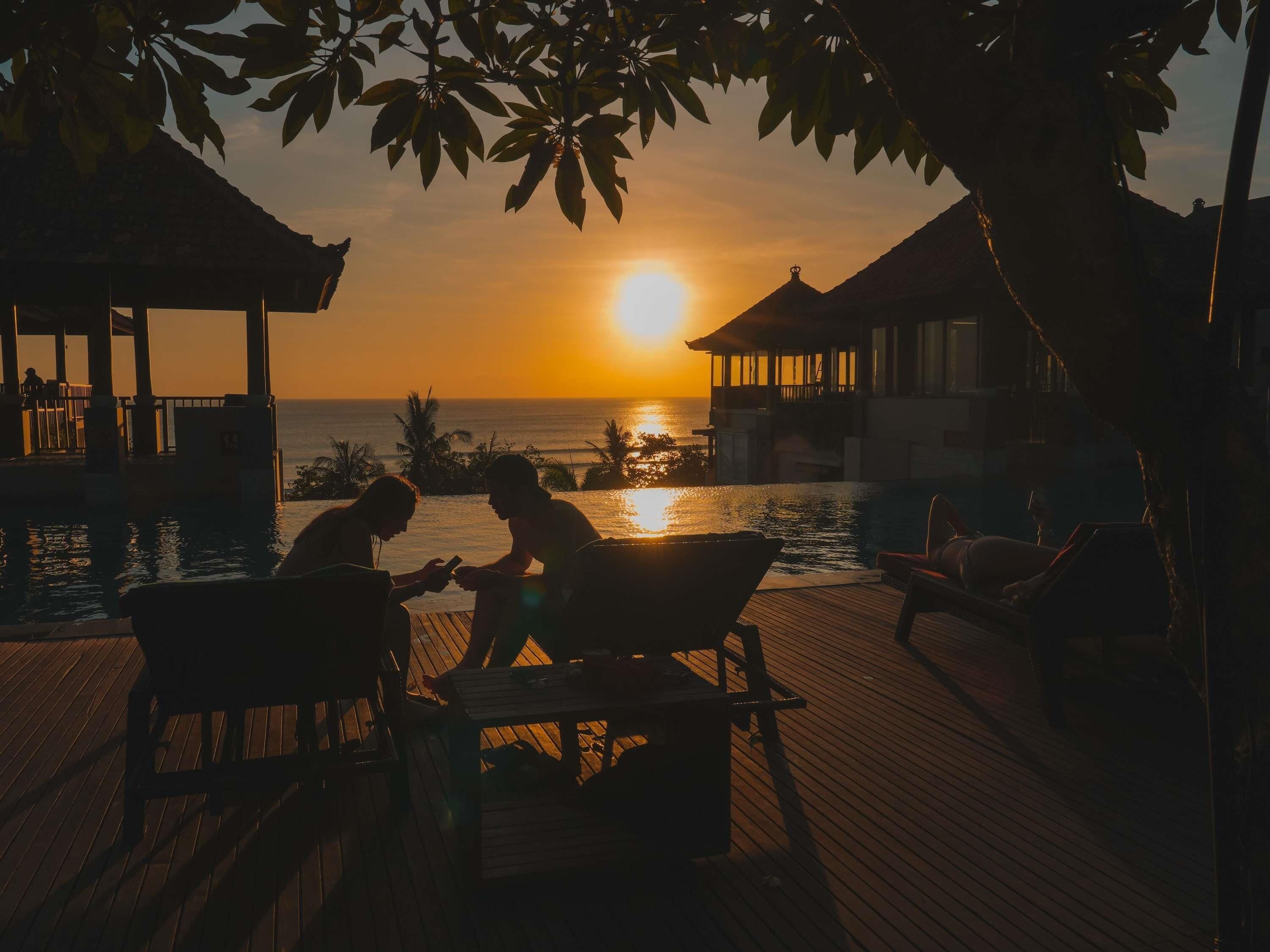 Ein Sonnenuntergangsblick von einer Bungalowanlage mit Pool und Liegestühlen.