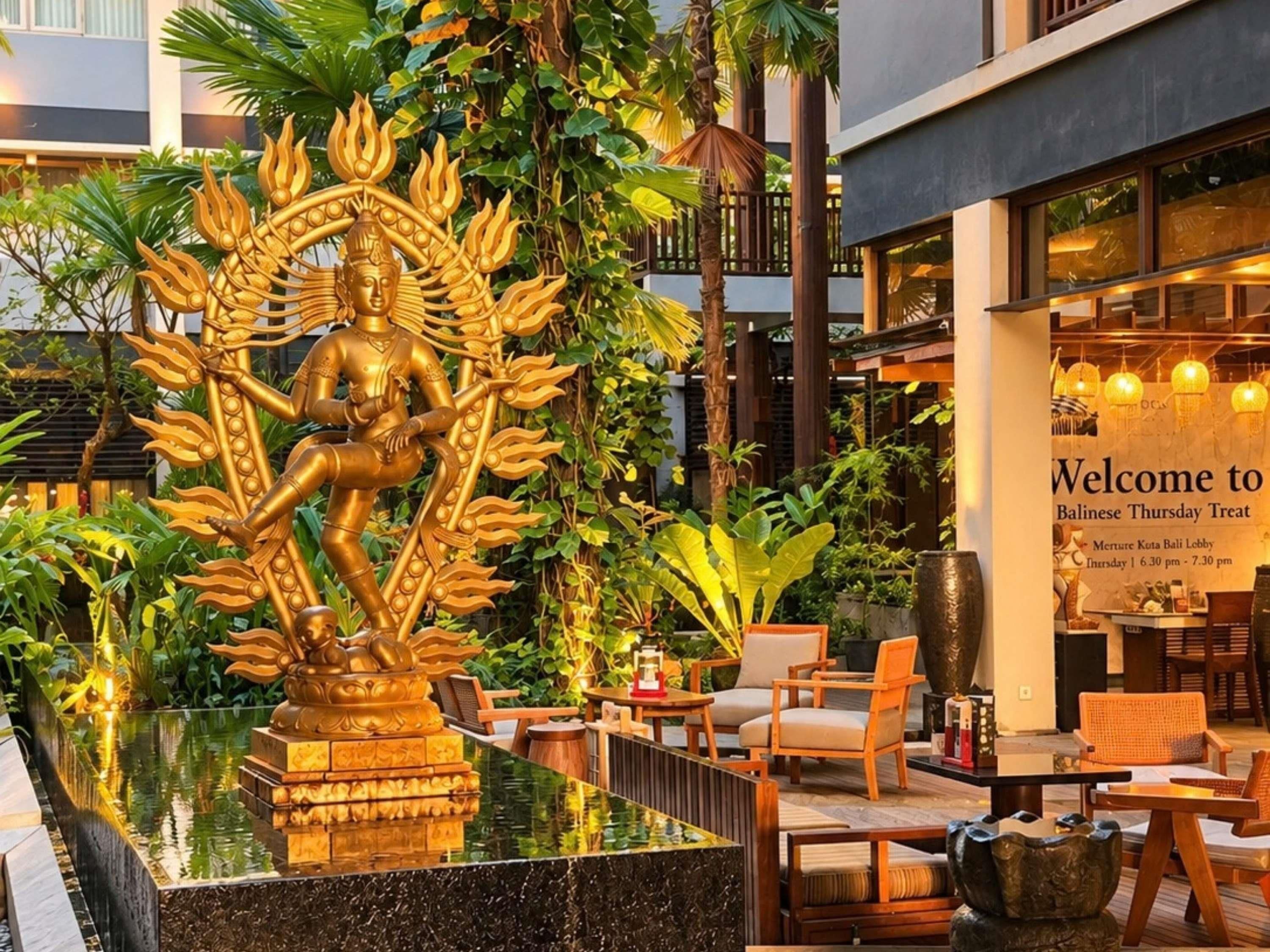 A Balinese-themed outdoor area with a golden statue, seating, and a sign for the Balinese Thursday Treat.