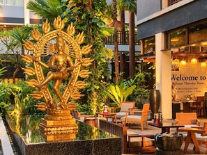 A Balinese-themed outdoor area with a golden statue, seating, and a sign for the Balinese Thursday Treat.