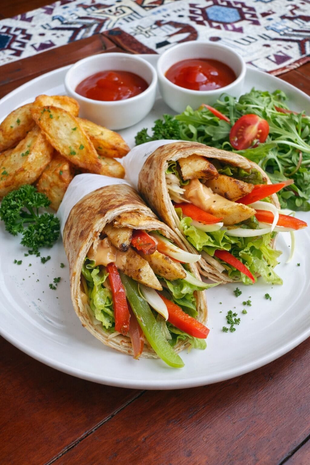 A plate with a wrap sandwich, fries, and a salad.
