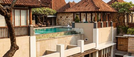 Un immeuble à plusieurs étages doté d’une piscine, d’un espace extérieur aménagé et d’une façade en pierre.