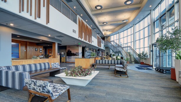 A spacious lobby with a reception desk, seating areas, and a staircase leading to upper floors. - Dimond Center Hotel (Anchorage)