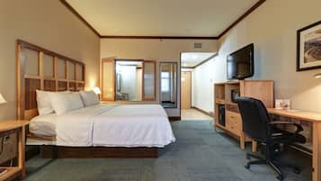 Habitación de hotel con cama, escritorio, silla, televisor y armario.