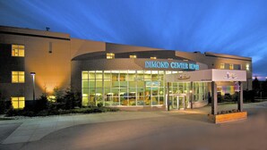 The exterior of the Diamond Center Hotel with a glass facade and a sign above the entrance. - Dimond Center Hotel (Anchorage)