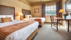 Une chambre d’hôtel avec deux lits, un bureau et une chaise.
