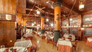 Un restaurant au décor intérieur en bois, doté de nombreuses tables et de ventilateurs de plafond.