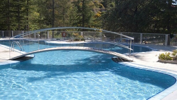 Une piscine dotée d’un pont de verre et d’une terrasse carrelée.