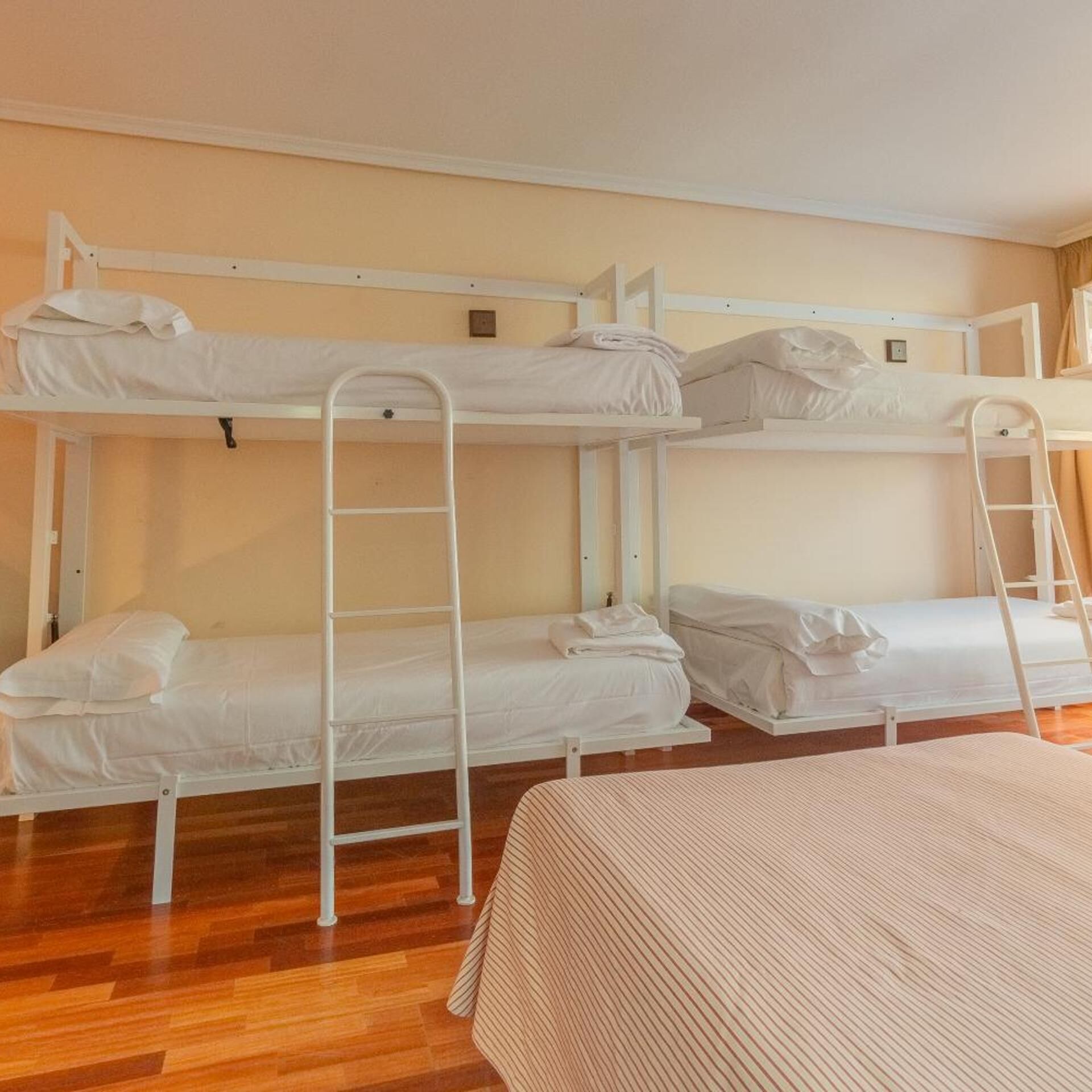 Habitación con literas, suelo de madera y camas blancas.