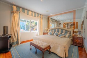 Un dormitorio con una cama grande, un banco de madera, un aparador y un espejo.