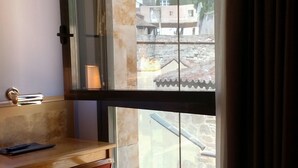 Una habitación con un escritorio de madera, una silla roja y un ventanal con vistas a un templo.