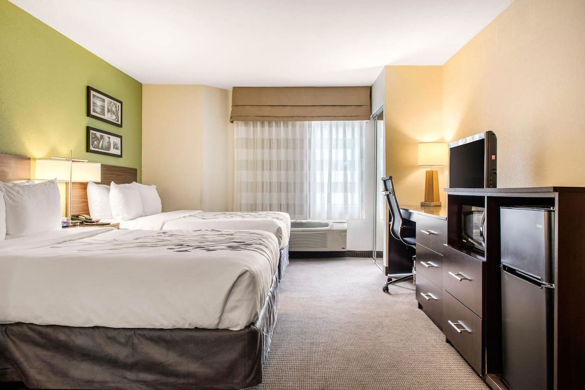 Une chambre d’hôtel équipée d’un lit, d’un bureau avec une chaise, d’une télévision et d’un mini-bar.