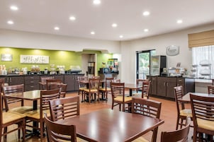 Un comedor con mesas y sillas de madera, una zona de cocina con una pared verde, y un letrero que dice "Morning Medley".