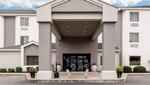 Un bâtiment moderne doté d’une entrée centrale, de grandes fenêtres et d’un aménagement paysager symétrique.