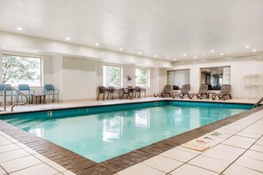 A swimming pool with lounge chairs and tables, large windows, and a tiled floor. - Sleep Inn & Suites Columbus South (Columbus)