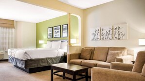 Une chambre d’hôtel avec un lit, un canapé, une table basse et des œuvres d’art murales.