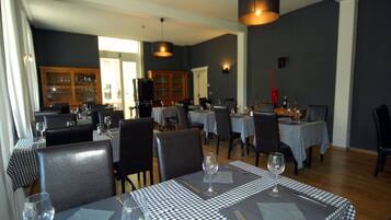 A dining area with checkered tablecloths, black chairs, and wine glasses set on each table.