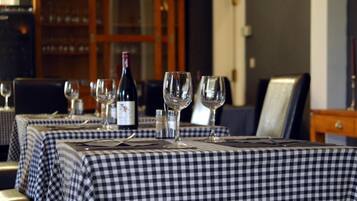 A dining area with checkered tablecloths, wine glasses, and a bottle of wine.
