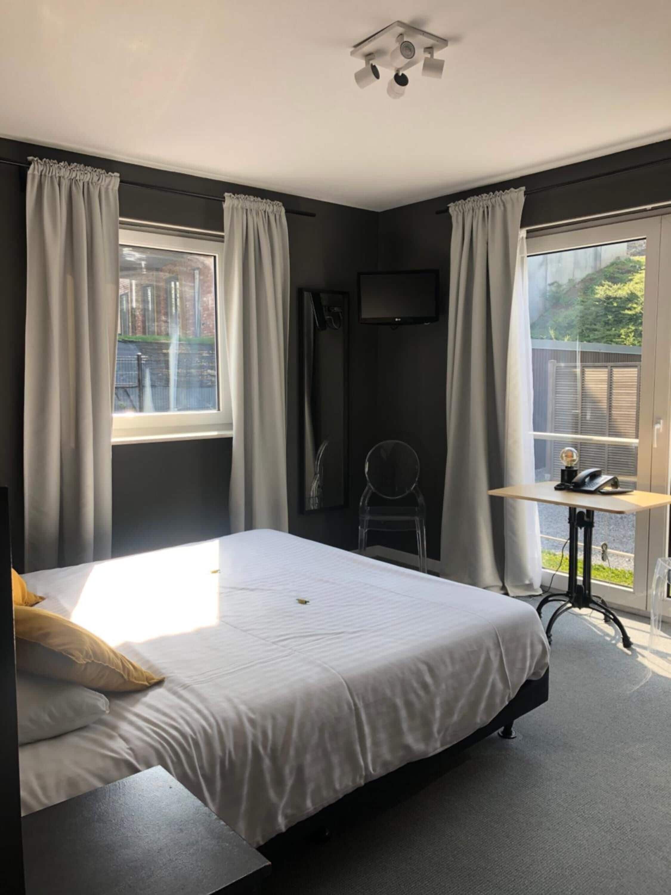 Um quarto moderno com uma cama grande, uma escrivaninha e uma televisão.