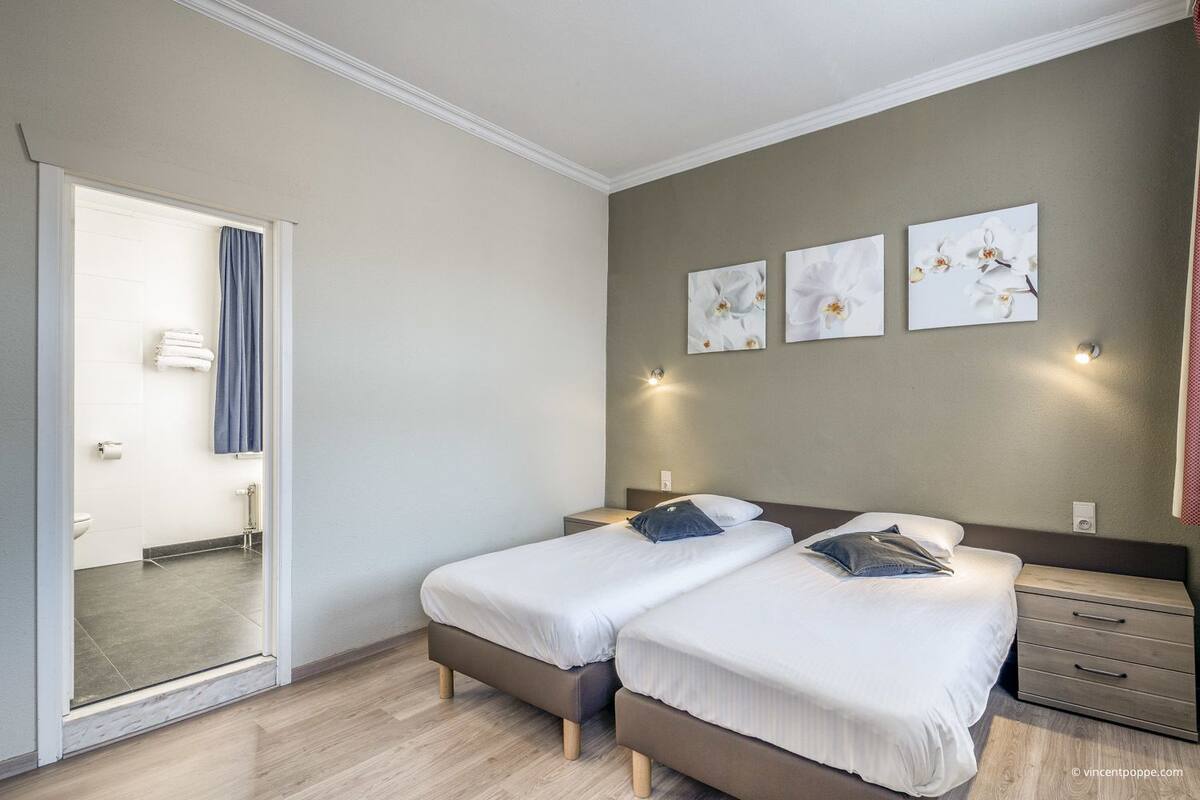 Een hotelkamer met twee bedden, een badkamer en uitzicht.