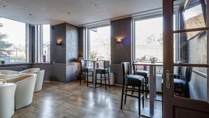 A modern interior with a wooden floor, a bar area, and large windows offering views of the outside.