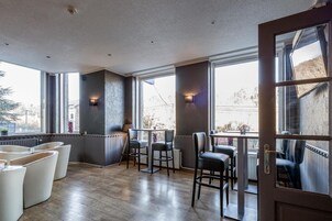 Un interior moderno con piso de madera, una zona de bar y grandes ventanales que ofrecen vistas al exterior.