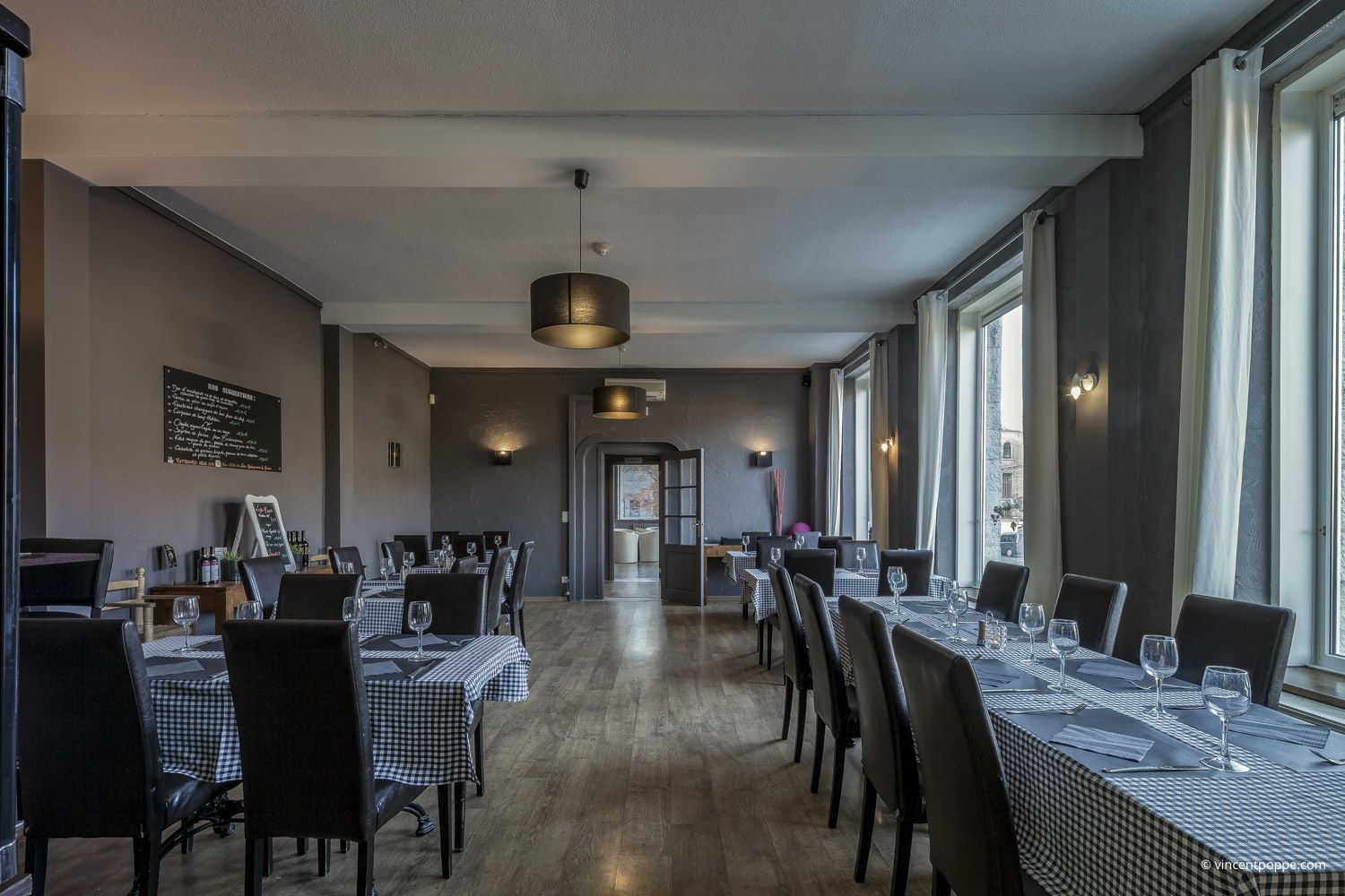 Un restaurante con manteles a cuadros, sillas negras y una barra larga.