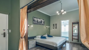 A bedroom with a bed, a nightstand, a wall-mounted light, a ceiling fan, and a view of the outdoors.