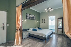 Un dormitorio con cama, mesita de noche, luz empotrada en la pared, ventilador de techo y vista al exterior.
